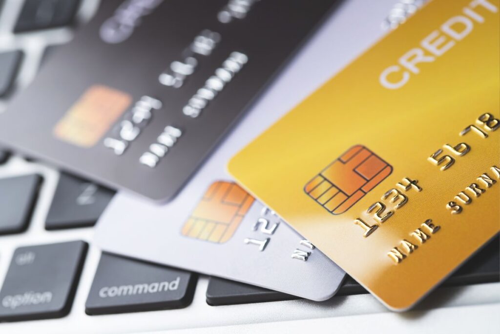 Vários cartões de crédito coloridos sobre um teclado de computador, ilustrando a comparação de taxas e juros entre diferentes bancos.