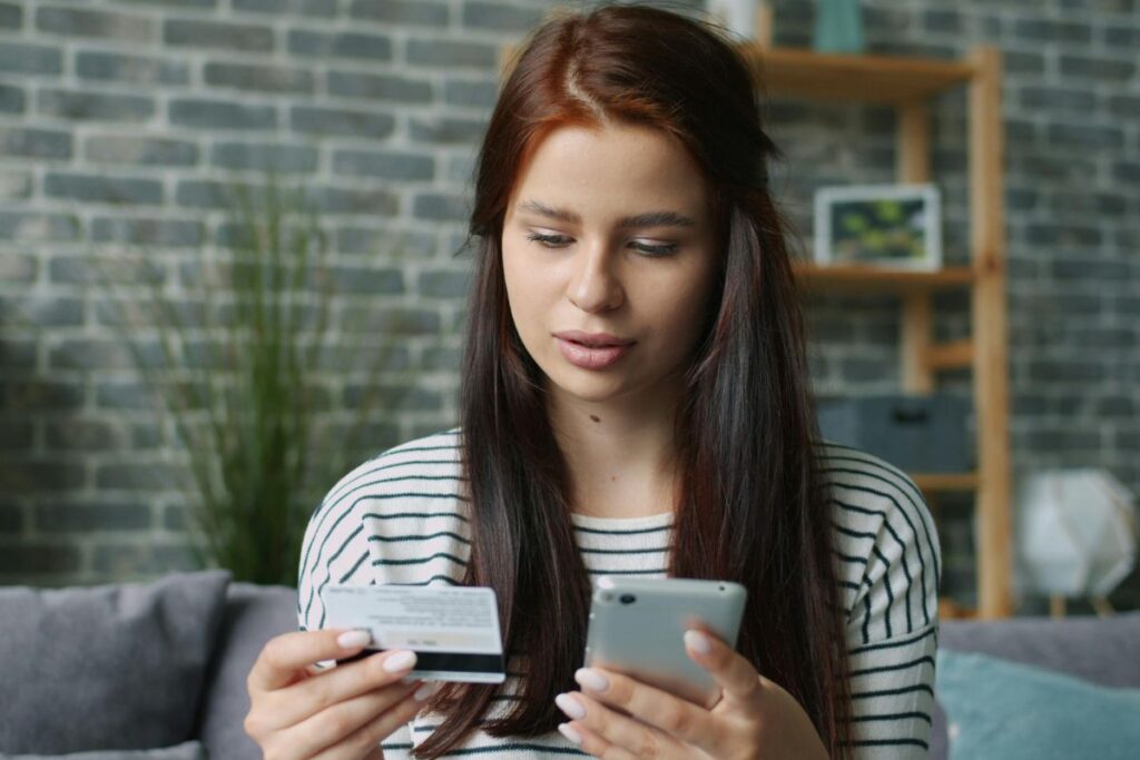 Jovem em casa conferindo os lançamentos da fatura do cartão de crédito para organizar o orçamento.